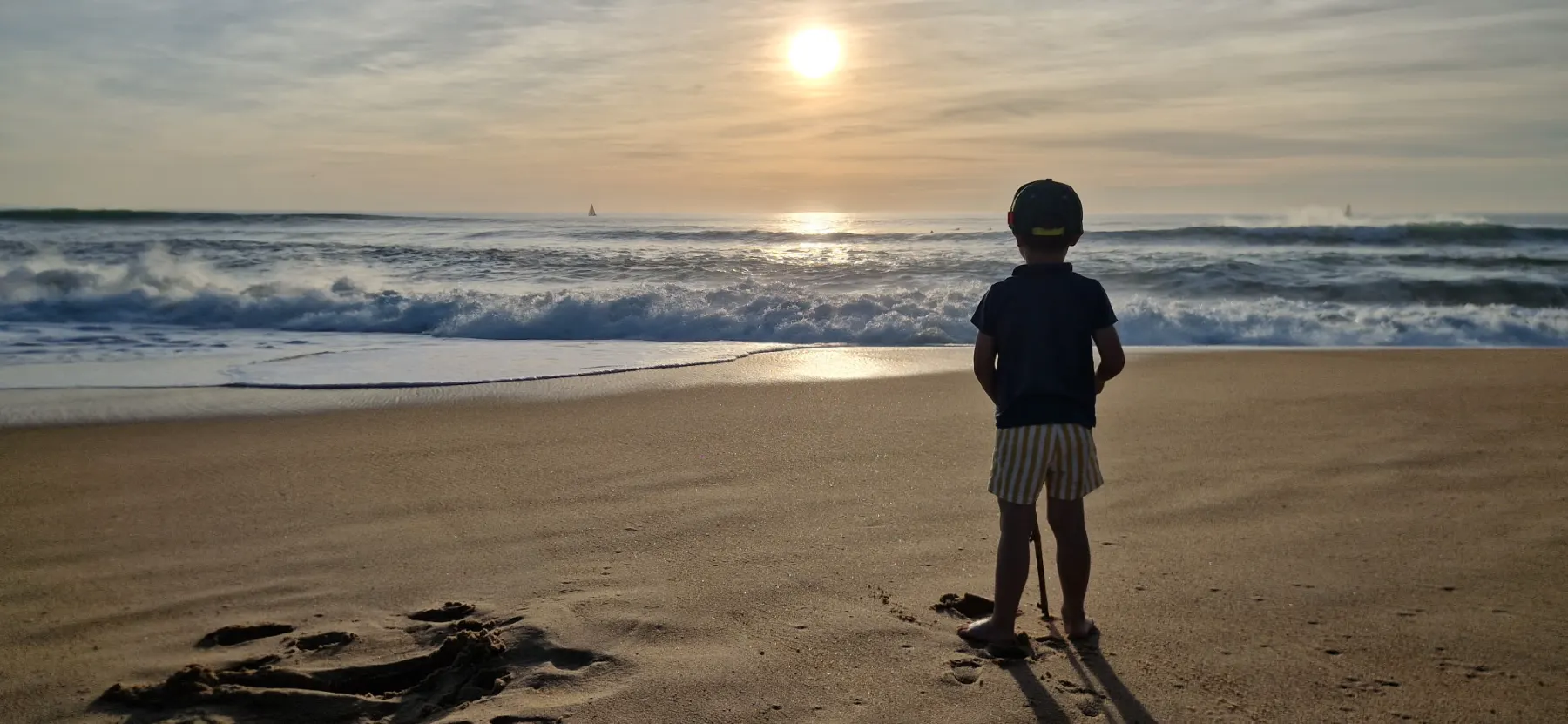 Enfant face à l'océan au coucher du soleil, vacances en famille à Seignosse